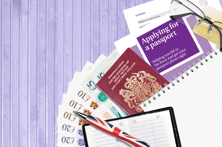 English violet guide Applying for a passport lies on table with office items. UK passport paperwork process